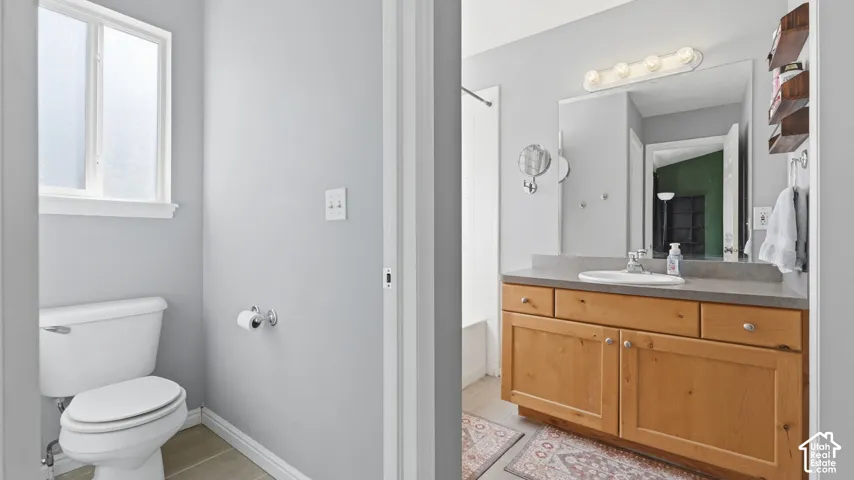 Private primary bathroom with generous vanity storage, large mirror, natural light, and separate toilet area.