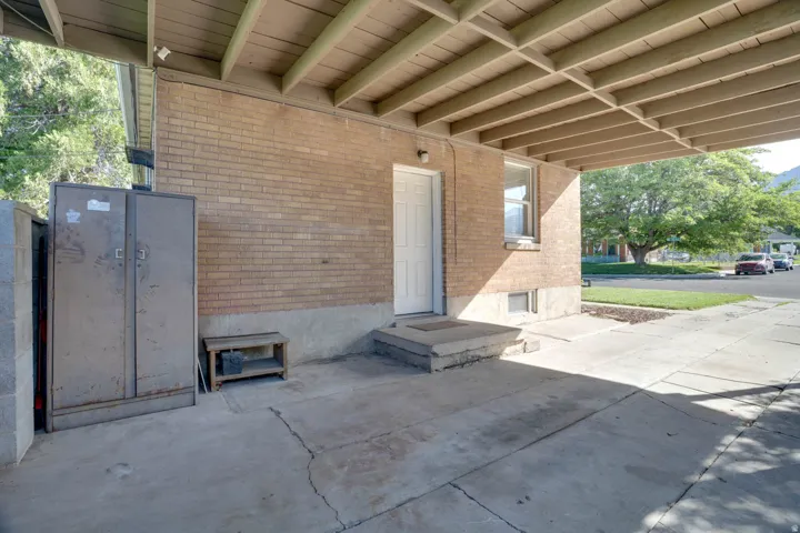 Brick exterior with covered carport, concrete steps, and a white entry door