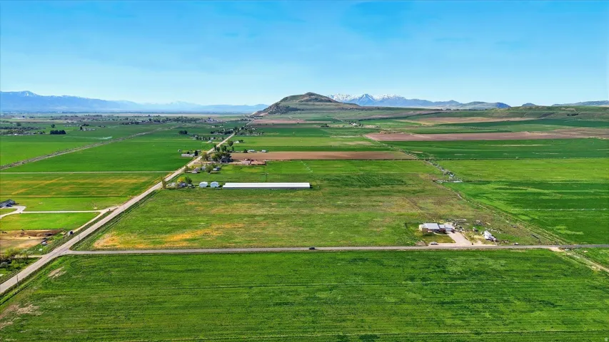 Expansive green fields with distant mountains under a clear sky