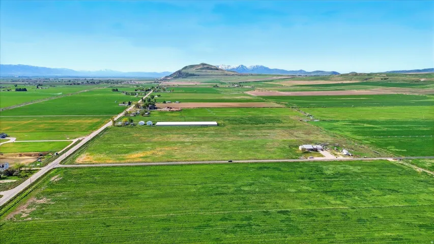 Expansive agricultural land featuring a clear sky, distant mountains, and established roads