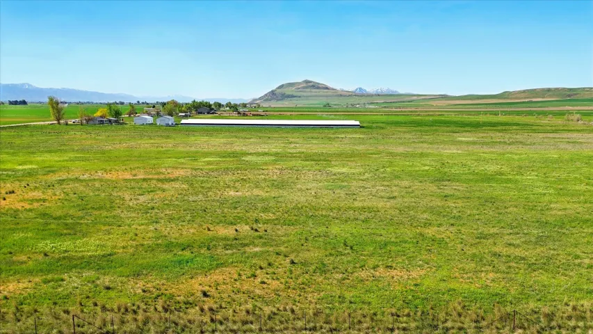 Expansive open land with distant mountain ranges and scattered residential structures