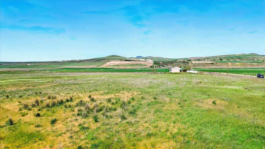 Expansive open land with distant rolling hills and a visible structure