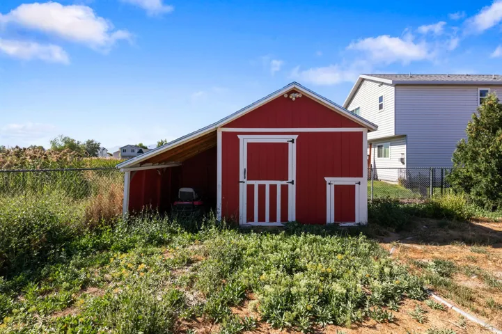 Red-painted storage shed with white trim, featuring a main entry door and a smaller access door