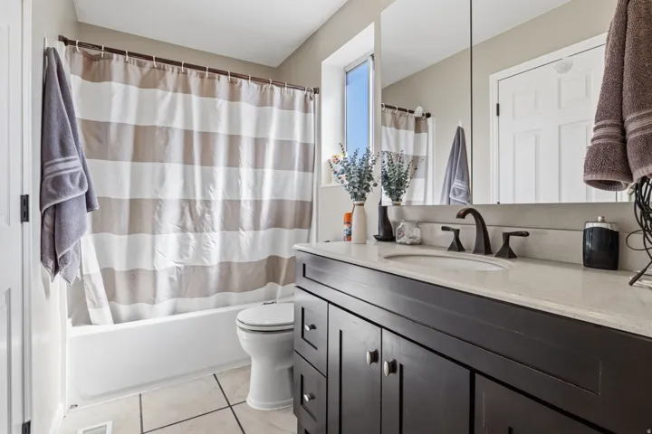 Dark wood-finish vanity with a light countertop, integrated sink, and bronze-finish faucet