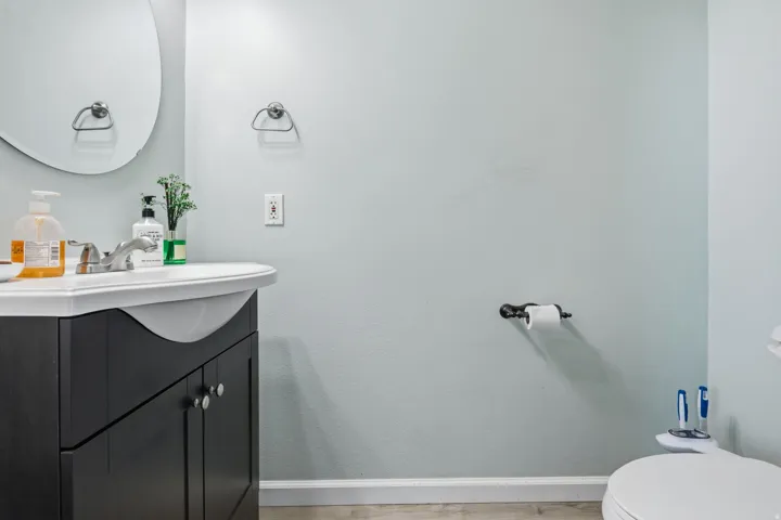 Contemporary vanity with integrated sink, brushed nickel faucet, and oval wall mirror