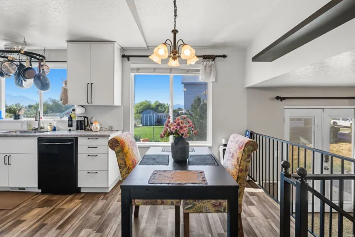 Wood-finish flooring, white cabinetry with dark hardware, built-in dishwasher, and a pot rack