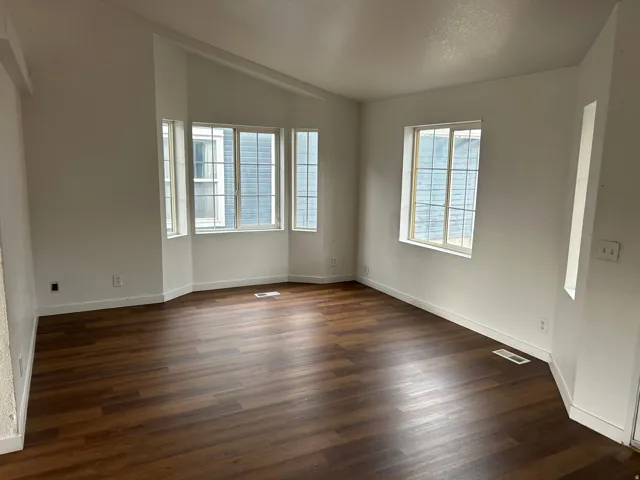 Expansive room featuring wood-finish flooring, multiple windows, and a bay window