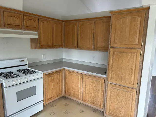 Wood-finish cabinetry, white range, and expansive countertop space