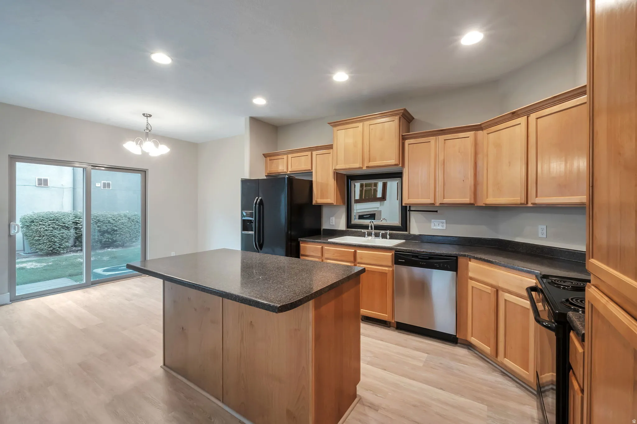 Kitchen with wood-finish flooring, recessed lighting, and a center island with a dark countertop
