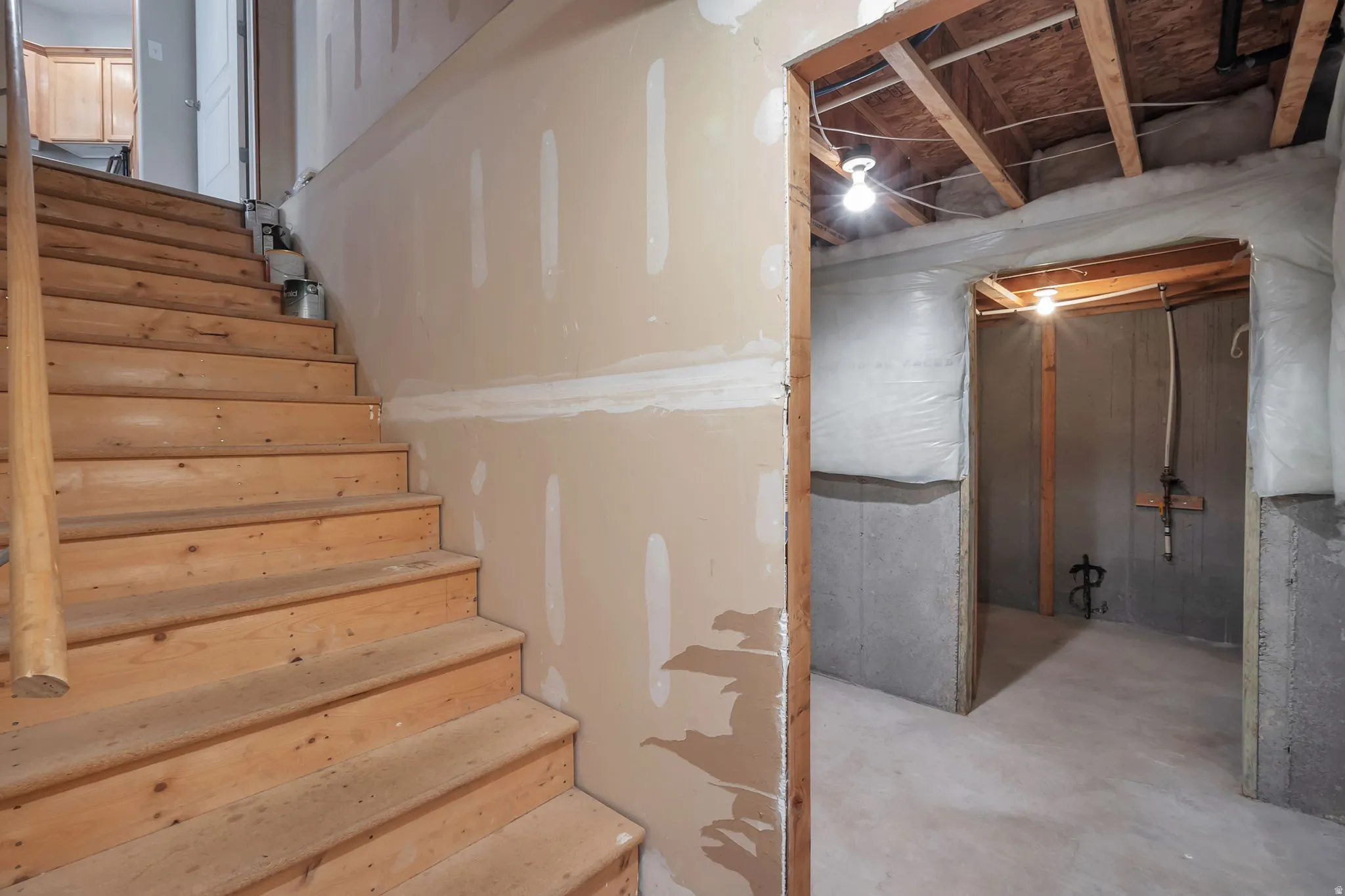 Unfinished basement featuring exposed wood ceiling joists and concrete block walls