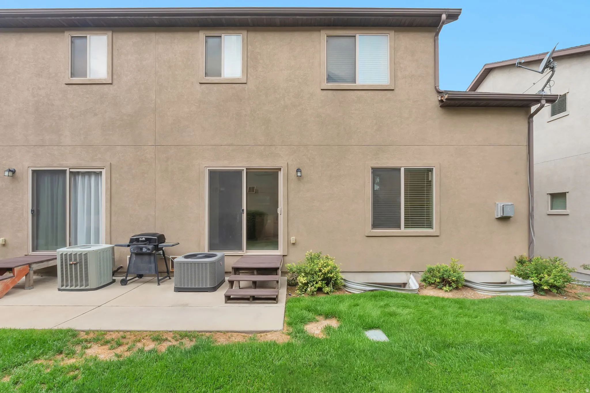 Exterior stucco finish with multiple windows and sliding glass doors