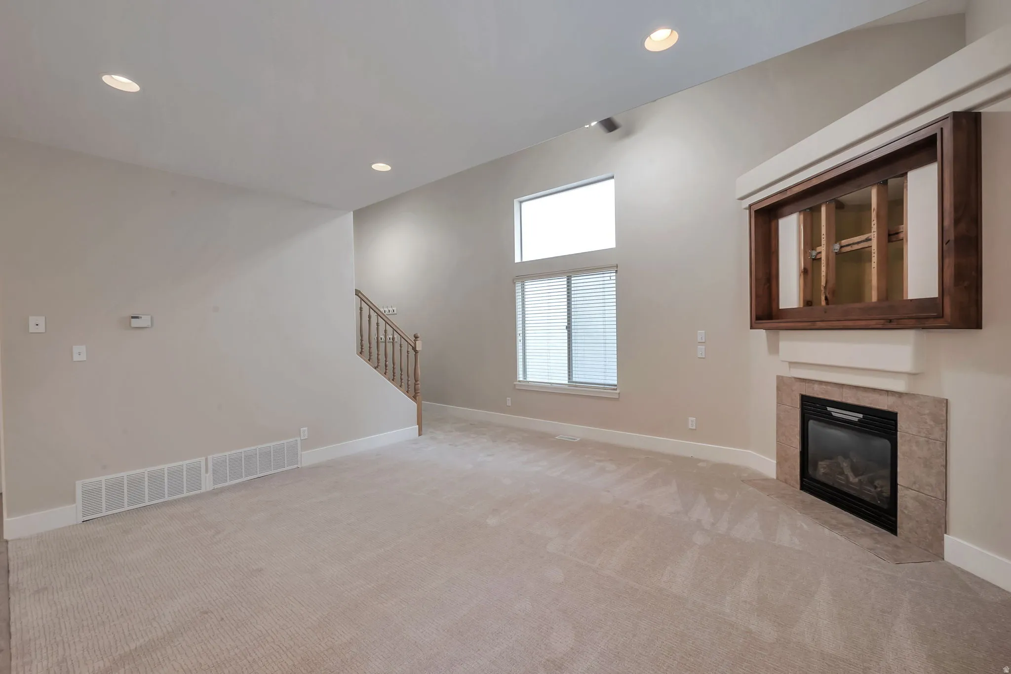 Living room with vaulted ceilings, recessed lighting, and a gas fireplace with a tiled surround