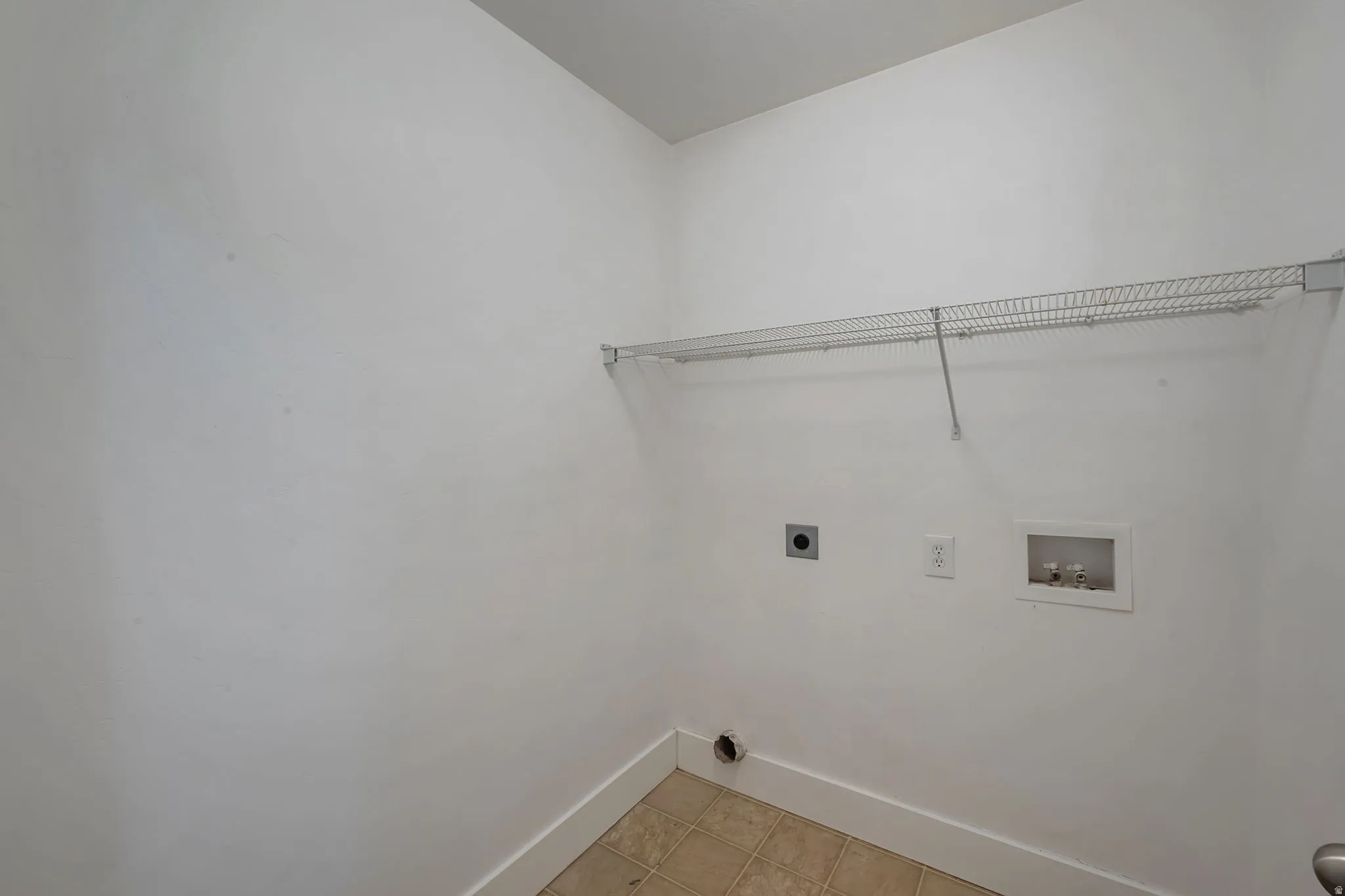 Upstairs laundry area with tile flooring and a wire shelving unit