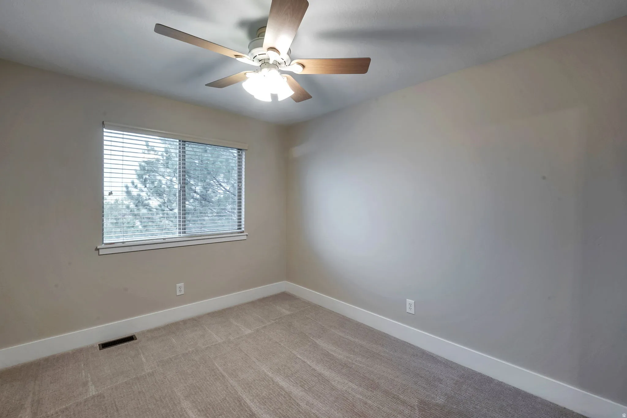 Neutral wall color, window with horizontal blinds, ceiling fan with light fixture, and carpet flooring