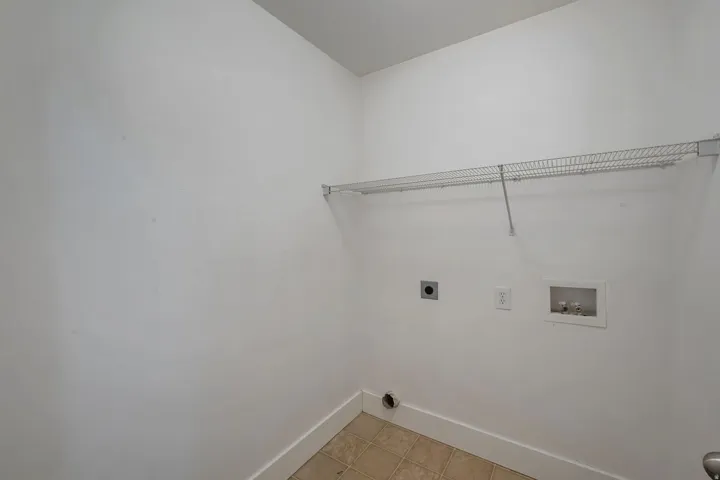 Upstairs laundry area with tile flooring and a wire shelving unit