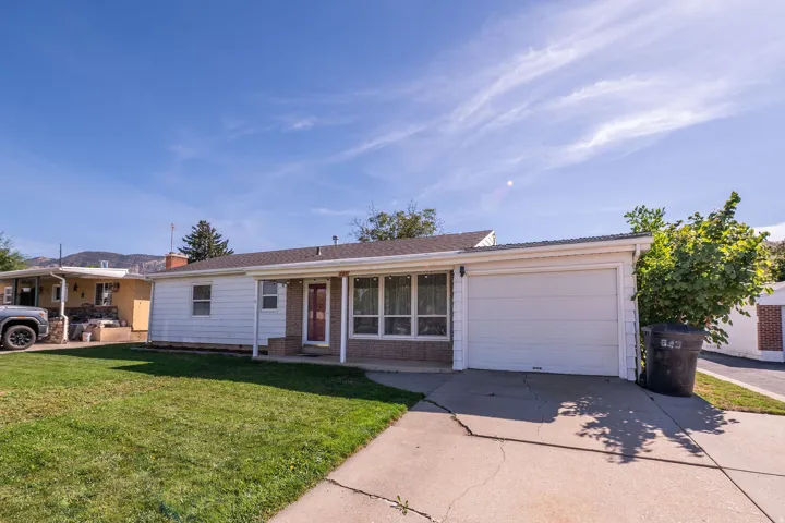 Single-story residence with white siding, an attached garage, a red entry door, and a front lawn