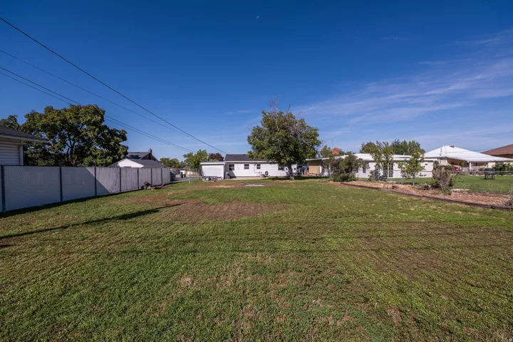 Expansive grassy area with a partial privacy fence