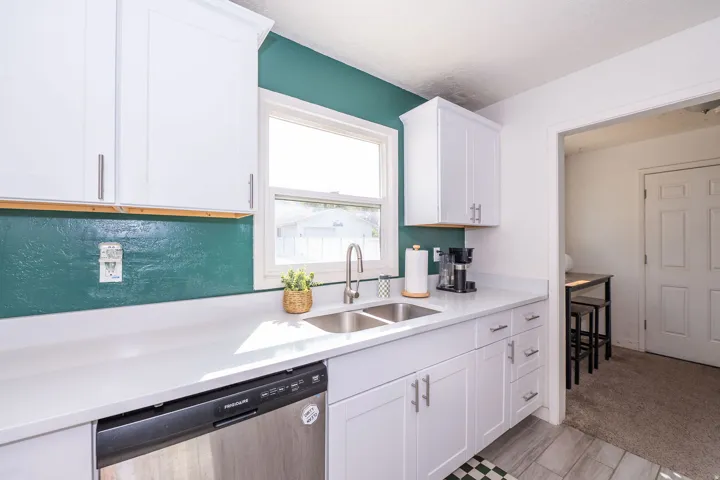 White cabinetry with brushed nickel hardware, light-toned countertops, and a double basin sink with a high-arc faucet