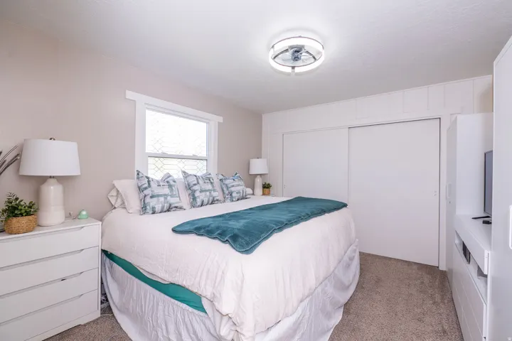 Recessed window with white trim, built-in sliding closet doors, ceiling-mounted light fixture, and neutral carpeting