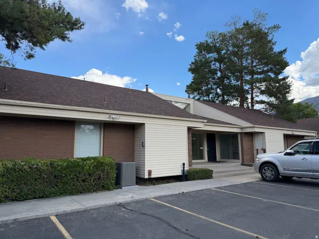 Exterior featuring a brown shingle roof, light-colored siding, and brick accents