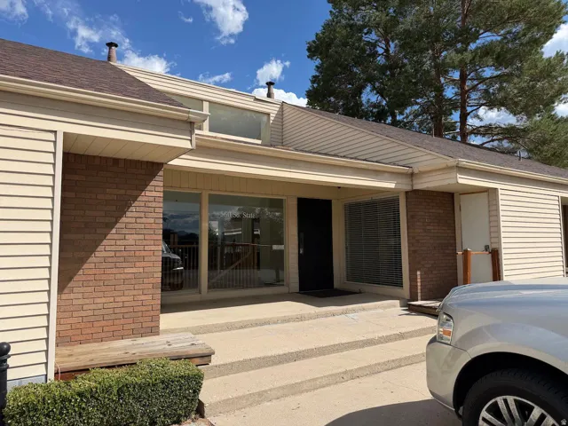 Brick and siding exterior with a multi-level roofline, large storefront windows, and a concrete entry staircase