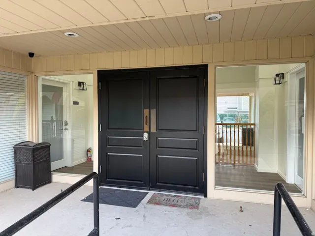Double entry doors with paneled detailing, complemented by sidelight windows and overhead recessed lighting