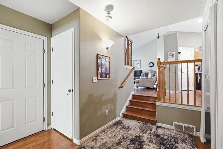 Wood-finish flooring, white panel doors, and a wood banister with balusters