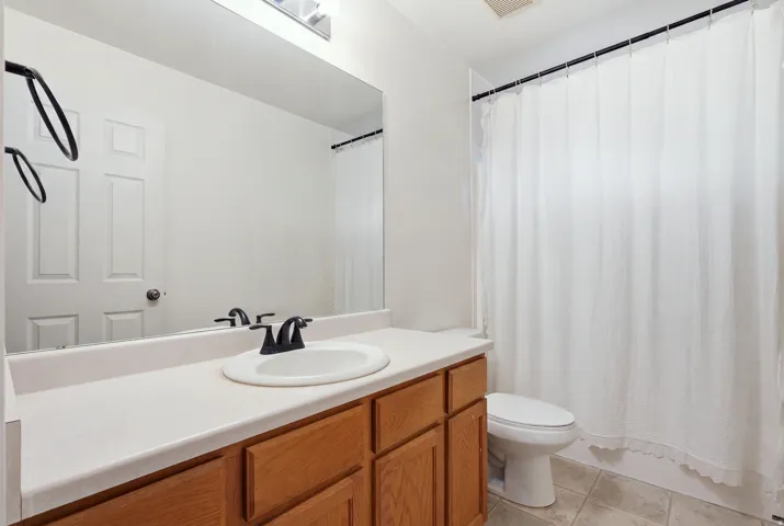 Vanity with wood-finish cabinetry, integrated sink, and dark-finish faucet