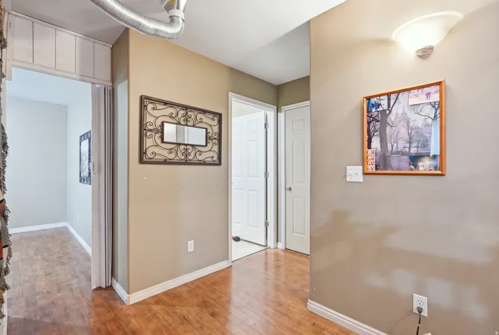 Wood-finish flooring throughout, neutral wall tones, white trim, and a wall-mounted sconce