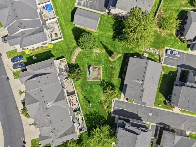 Multiple residential buildings with dark gray roofs, surrounded by extensive green lawns and paved driveways