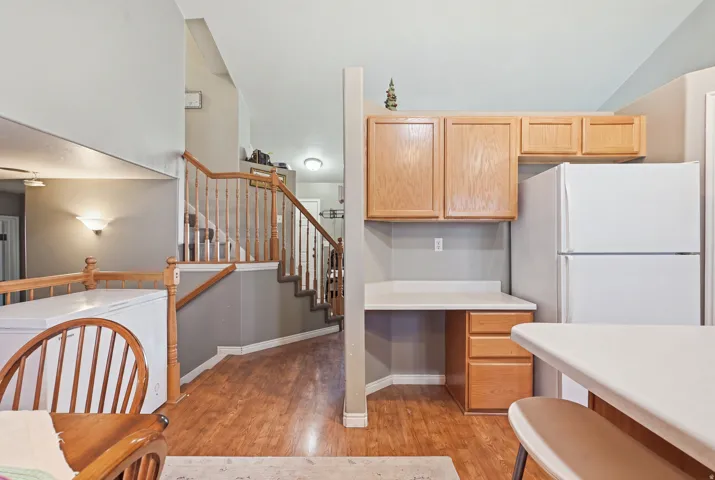 Wood-finish flooring, staircase with wood banister, built-in desk with wood drawers, and wall-mounted cabinetry