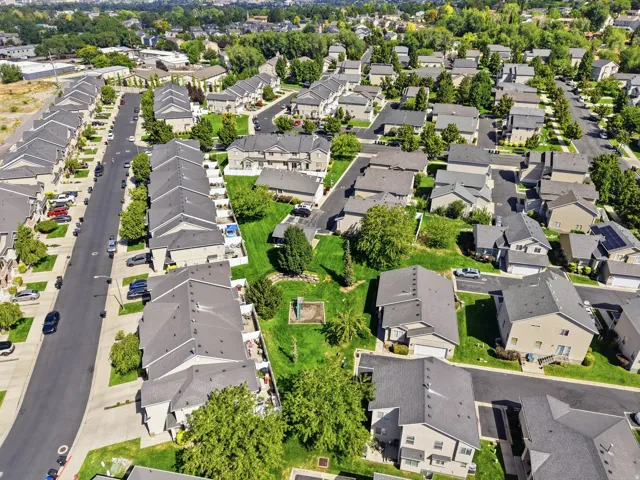 Residential community featuring multiple detached and attached dwellings, asphalt roadways, and mature landscaping