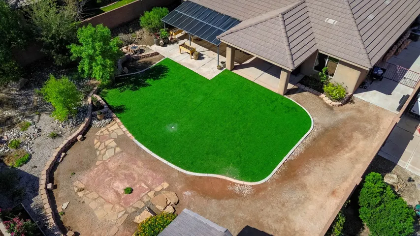 Expansive artificial turf lawn, covered patio, solar panel array, tiled roof, and natural stone hardscaping