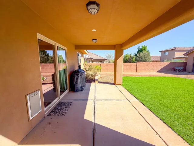 Covered patio with recessed lighting, large sliding glass door, and an artificial turf lawn