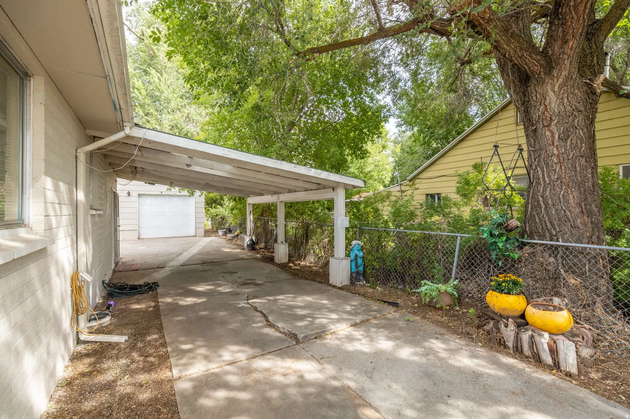 Carport structure with a paved driveway and mature trees
