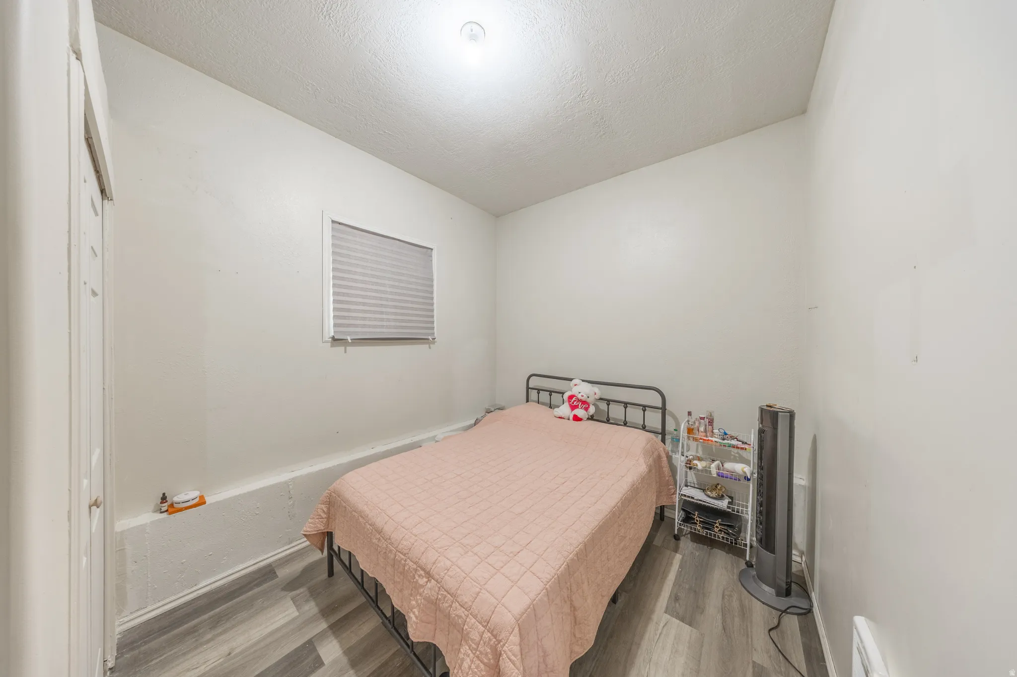 Recessed window with privacy blinds, wood-finish flooring, and white painted walls