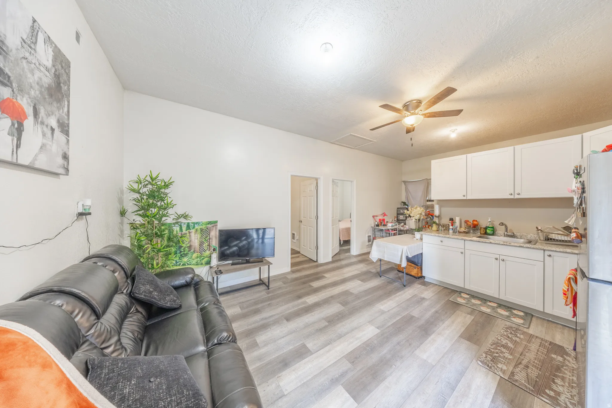 Open-concept living space with wood-finish flooring, white cabinetry, ceiling fan, and recessed lighting