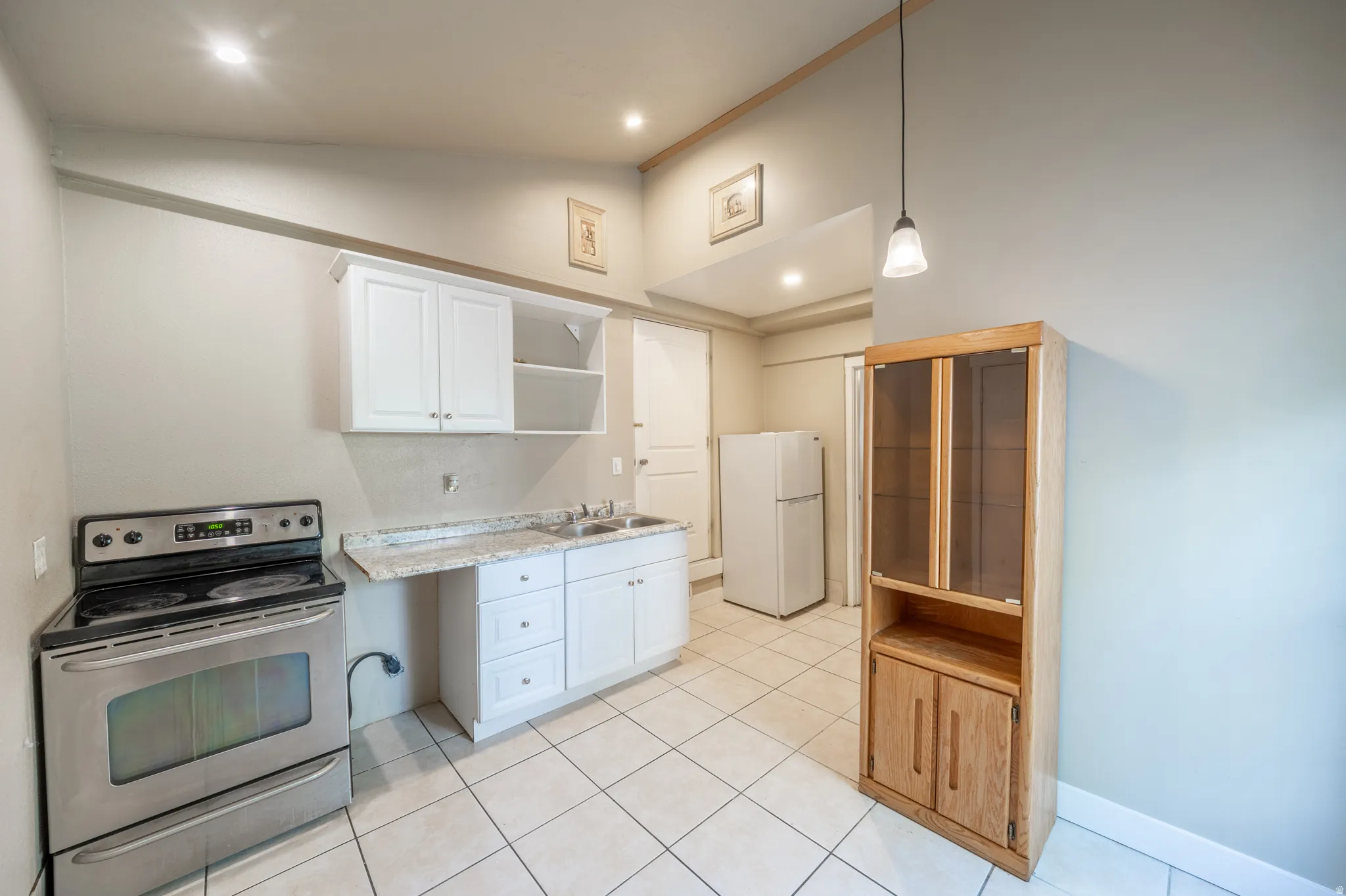 Kitchen featuring white cabinetry, light-toned countertop, stainless steel range, and tile flooring
