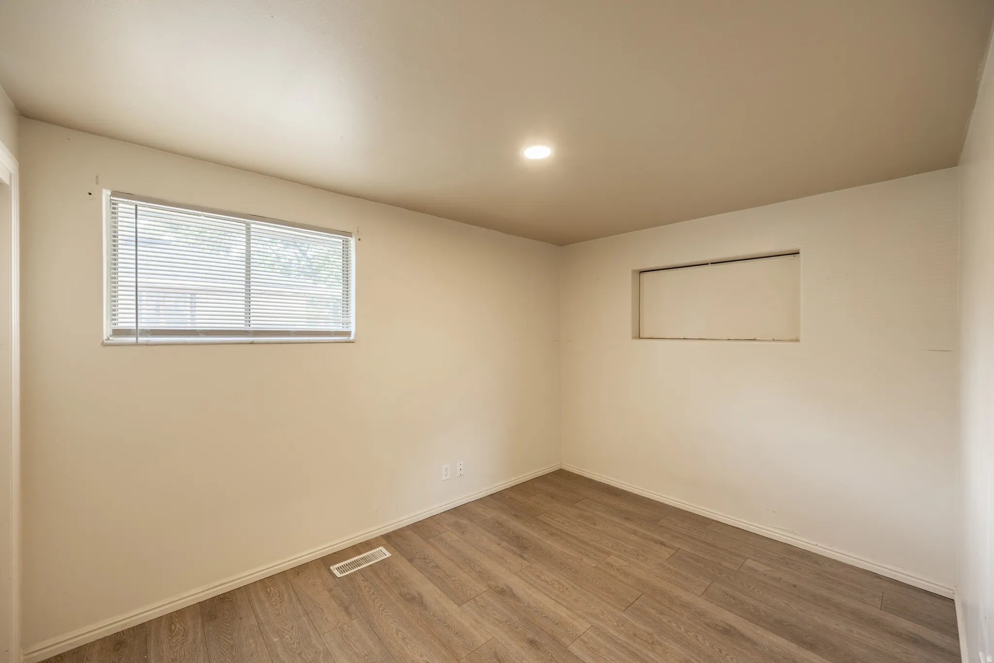 Recessed lighting, wood-finish flooring, and a single window with blinds