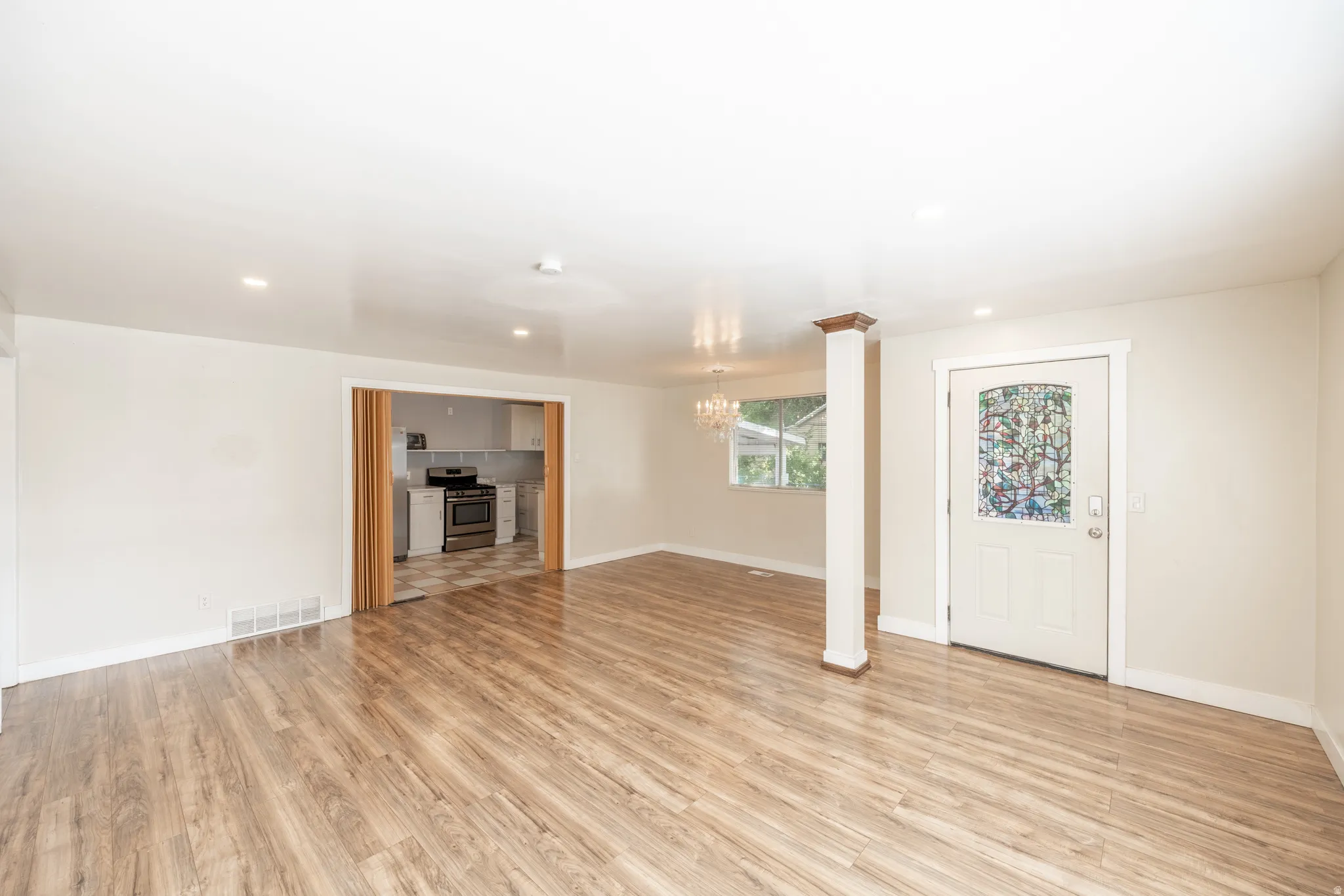 Wood-finish flooring throughout, recessed lighting, and a decorative stained-glass entry door