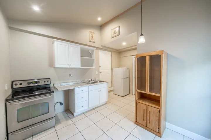 Kitchen featuring white cabinetry, light-toned countertop, stainless steel range, and tile flooring