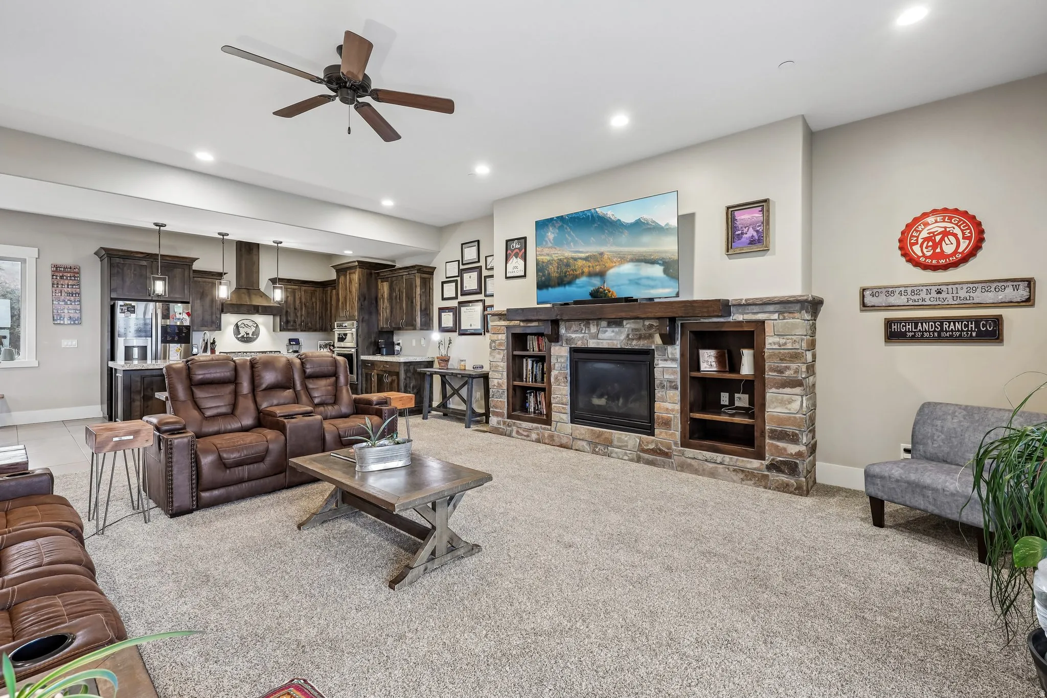 Wide-angle view of the open main level showing the stone fireplace, built-in cabinetry, kitchen and dining area in a Rustler at Hideout home.