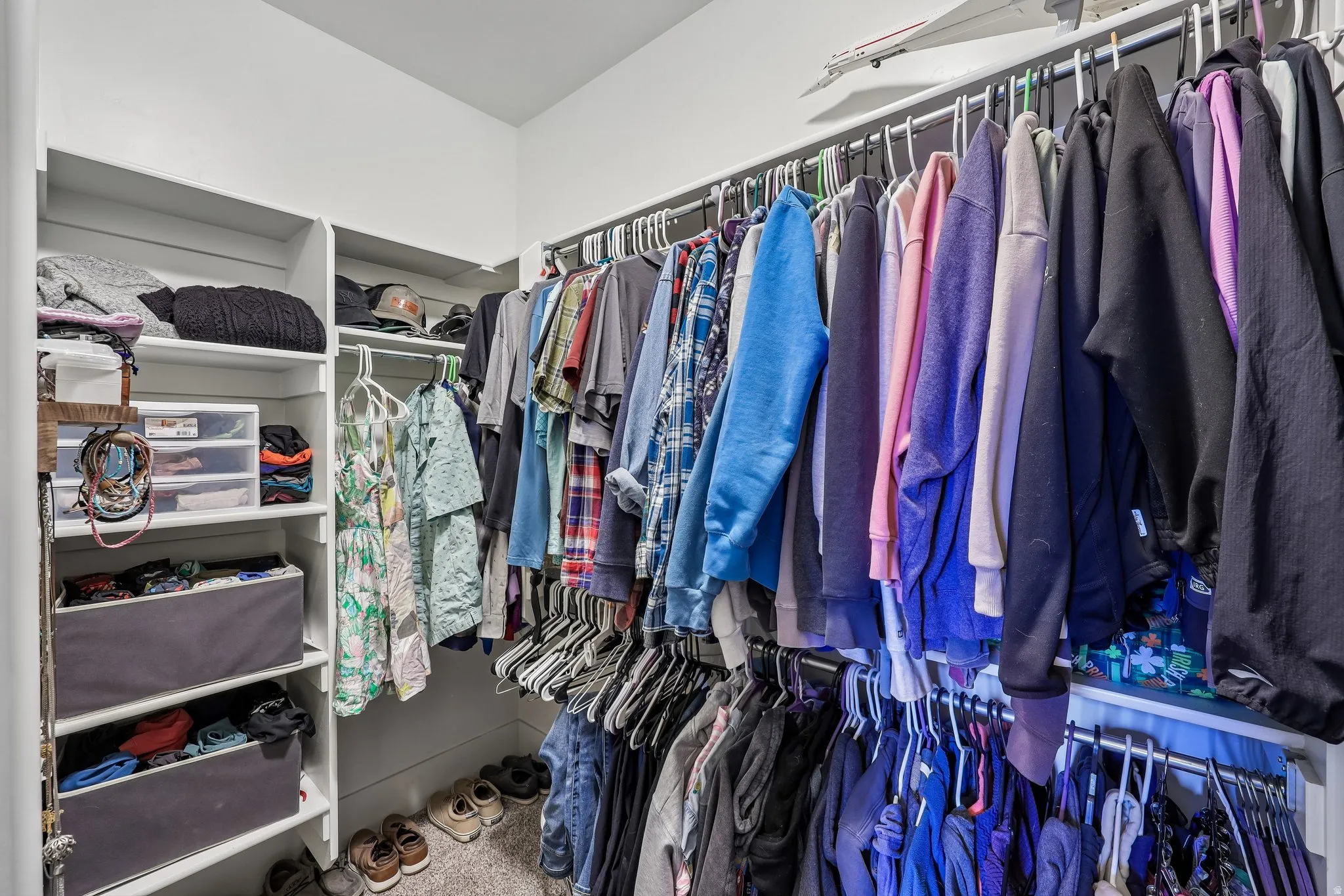 Primary walk-in closet with built-in shelving, multiple hanging rods and carpet flooring in a Rustler at Hideout home.