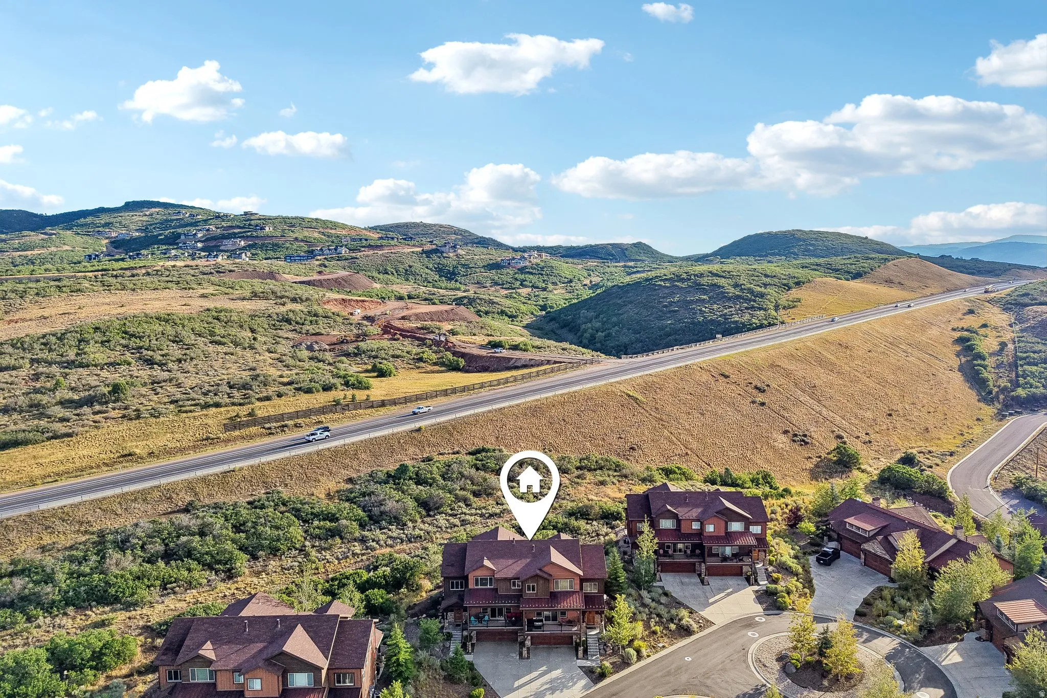 Aerial marking the home's site on a sloped lot in Rustler at Hideout, with multiple balconies, paver driveway and attached garage above Jordanelle Reservoir.