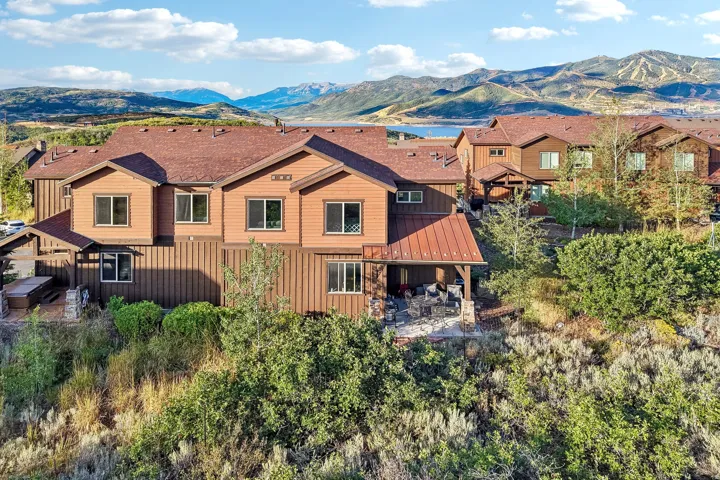 Rear elevation showing brown wood siding, a red metal roof and the covered outdoor patio in Rustler at Hideout, Hideout, Utah.