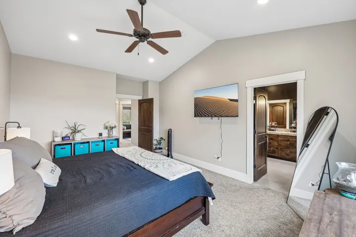 Primary suite with a vaulted ceiling, ensuite bathroom and walk-in closet opening off the room in a Hideout, Utah home.