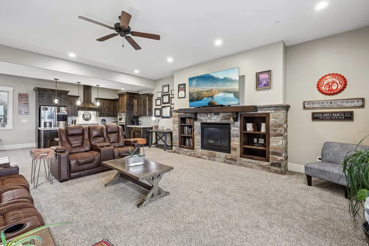 Wide-angle view of the open main level showing the stone fireplace, built-in cabinetry, kitchen and dining area in a Rustler at Hideout home.