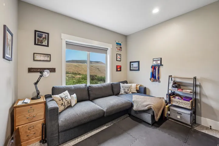 Third upstairs bedroom used as a lounge, with a sectional, desk area and hillside window in a Rustler at Hideout home.