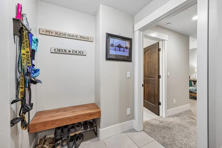 Mudroom gear drop with wall hooks, a built-in wood bench and shoe storage opening to the garage in a Hideout, Utah mountain home.