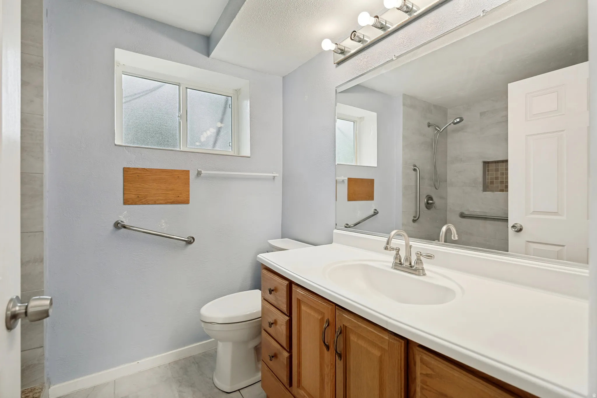 Bathroom featuring a single vanity with wood-finish cabinetry, white countertop, and integrated sink